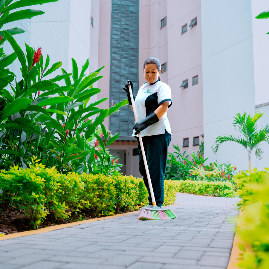 Operaria de limpieza mopeando piso de pasillo en edificio de apartamentos o conjunto residencial.