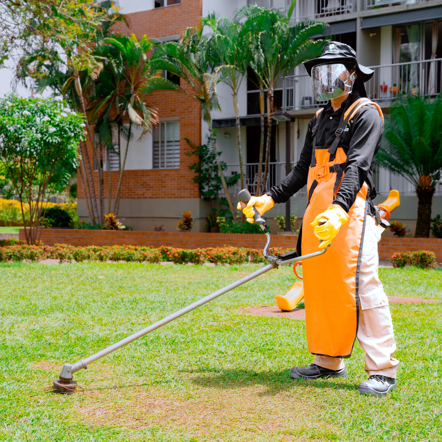Primer plano de técnico con careta protectora aplicando tratamiento fitosanitario en las áreas verdes de un complejo de apartamentos en Cali.