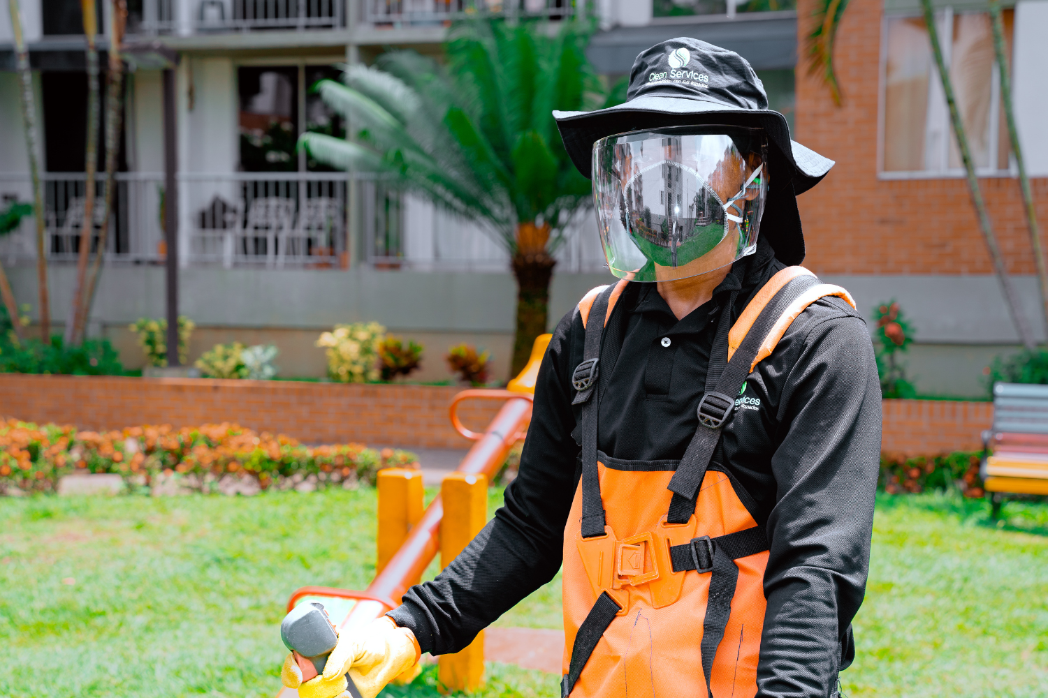 Especialista con equipo de aspersión y protección aplicando tratamiento fitosanitario en áreas verdes de conjunto residencial en Cali.