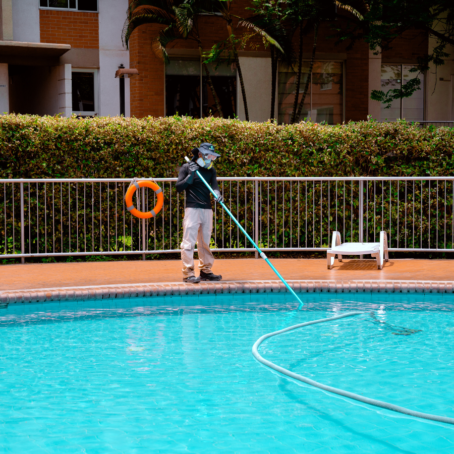 Jardinero uniformado de Clean Services realizando labores de poda y mantenimiento en un jardín bien cuidado de un conjunto residencial en el sur de Cali